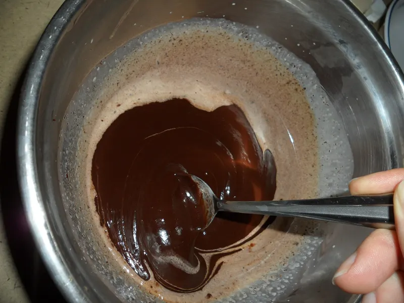 Dark chocolate being stirred as it melts in a pan