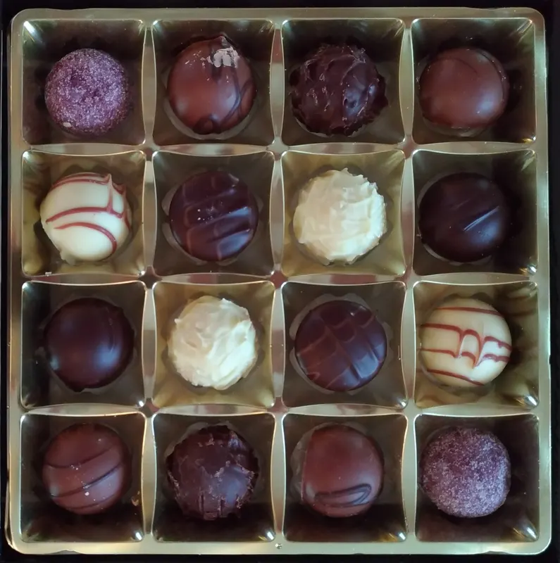 A box of chocolate truffles dusted with cocoa, coconut and nuts